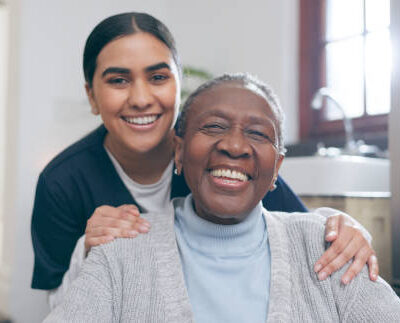 Smile, healthcare and portrait of nurse with patient in a wheelchair for discussion at nursing home. Medical career, happy and young female caregiver with senior black woman with disability in house.