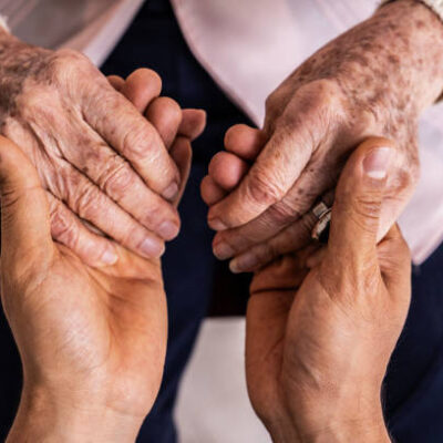 Close-up of a caregiver holding hands senior woman patient